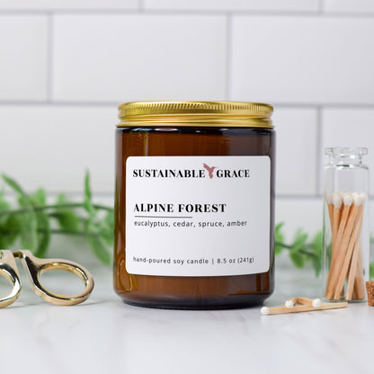 alpine forest blue spruce scented soy candle from sustainable grace in an amber colored jar with a gold lid