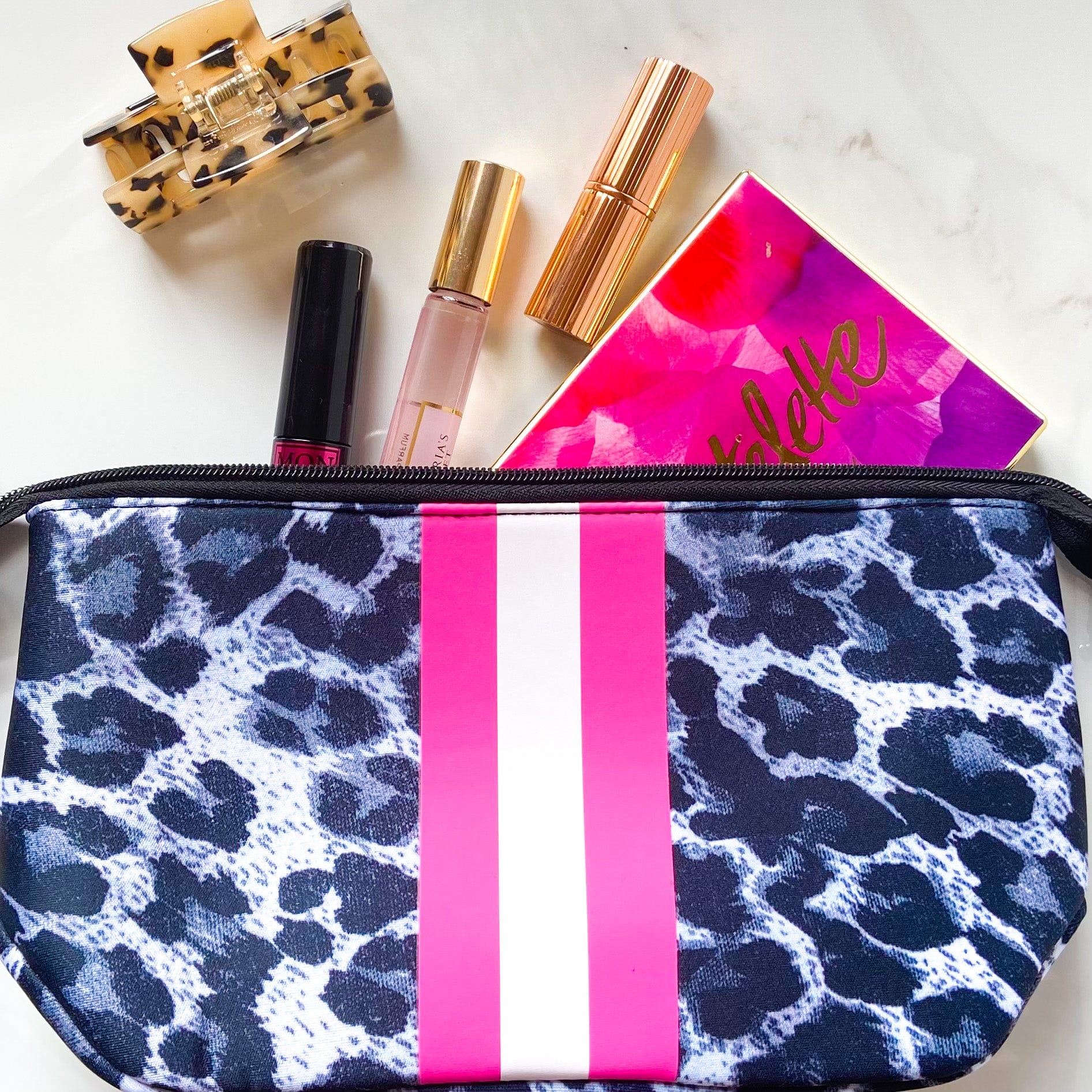 Neoprene makeup bag in white leopard styled with makeup and accessories